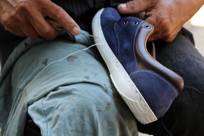 Midsection of man stitching shoe at workshop