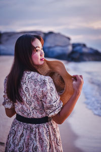Beautiful young woman looking at sea against sky