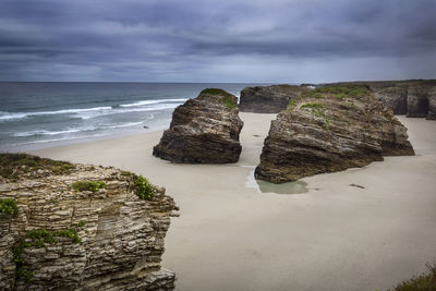 Scenic view of rocks on beach against sky