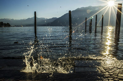 Wooden posts in lake against sky