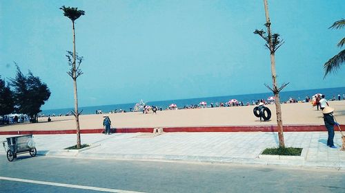 People at beach against clear blue sky