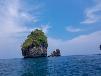 Rock formation in sea against blue sky