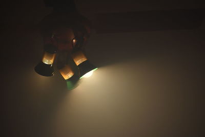 Close-up of hand holding illuminated light over black background
