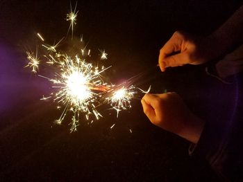 Close-up of hands over illuminated firework display at night