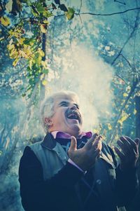 Smiling senior man standing against trees