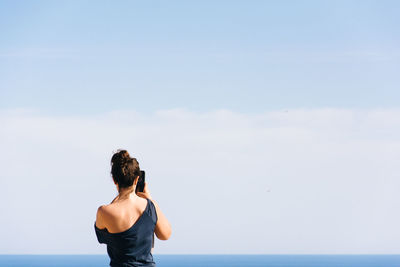Rear view of woman standing against sea and sky