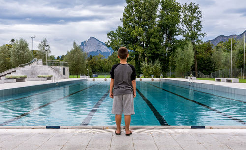 Rear view of boy standing at poolside