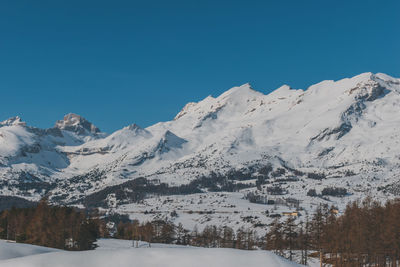 Scenic view of snowcapped mountains against clear blue sky