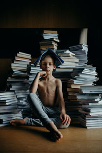 Boy sitting against stack of books