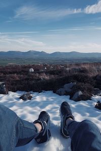 Low section of person standing on snow covered landscape