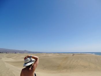 Woman on beach against clear blue sky