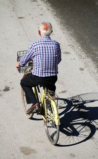 Rear view of man riding bicycle on street