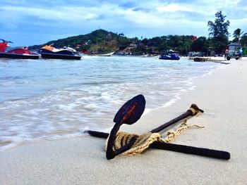 Boat moored on beach against sky