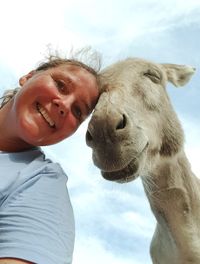 Low angle portrait of woman with horse against sky