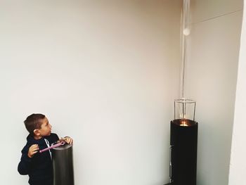 Boy performing scientific experiment against white wall