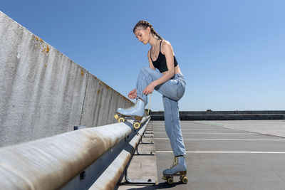 Girl tying up her roller skates, urban background