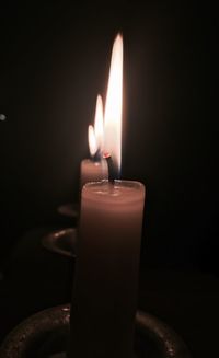 Close-up of illuminated candle in darkroom