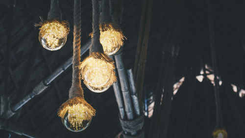 Low angle view of illuminated light bulb hanging at night