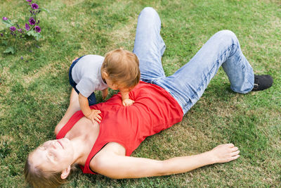 High angle view of mother with daughter lying on field at home