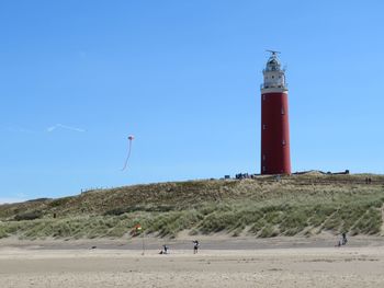 Lighthouse on beach against sky