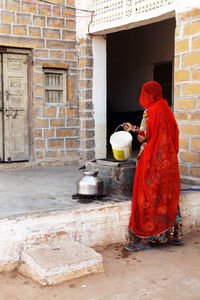 Woman wearing sari working outside house in village