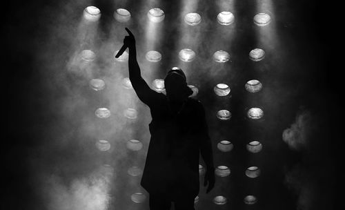 Performer with arms raised on stage