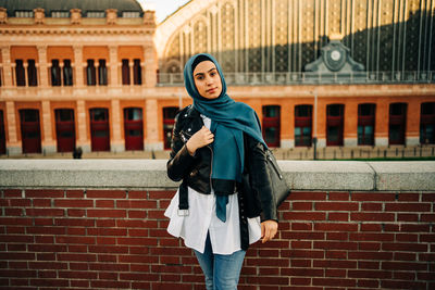 Portrait of woman standing against brick wall