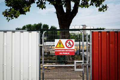 Information sign by tree against sky