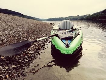 Boat moored on lake against sky