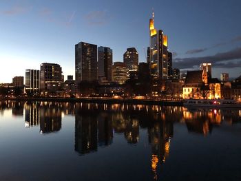 Reflection of illuminated buildings in river against sky