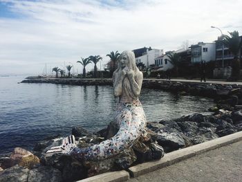 Statue by water against sky