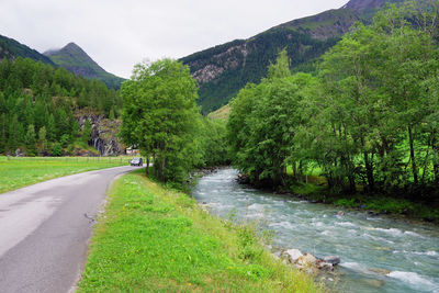 Road amidst trees and mountains against sky