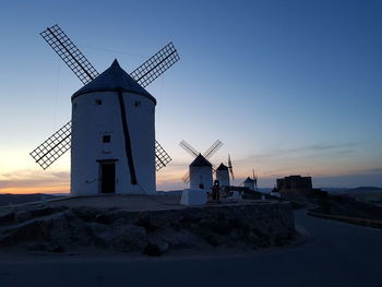 Traditional windmill on landscape against sky during sunset