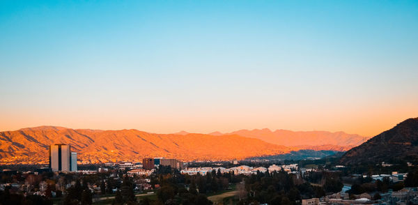 Houses in town against clear sky during sunset