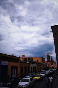 Cars on street amidst buildings in city against sky