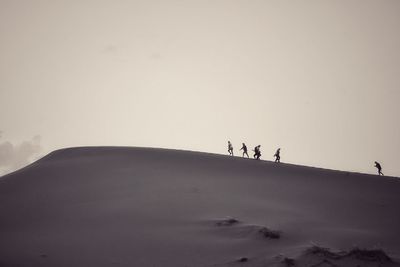 People on desert against clear sky during winter
