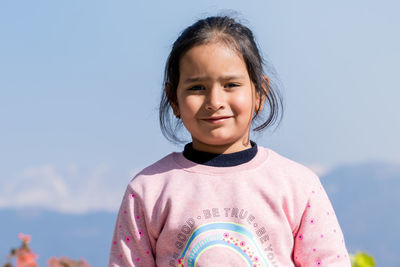 Portrait of young woman standing against clear sky