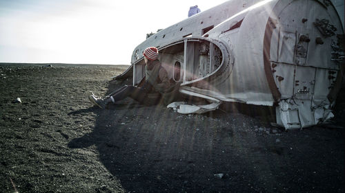 Woman sitting in front of airplane wreck