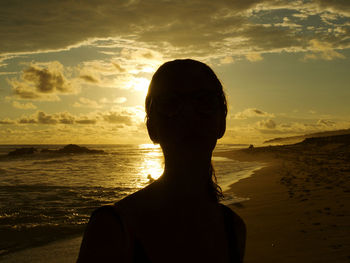 Portrait of woman on beach against sky during sunset