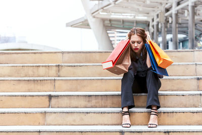 Tensed woman with shopping bags sitting on steps