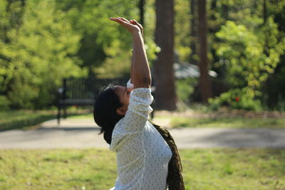 Side view of woman with arms raised exercising at park