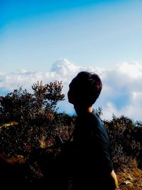 Rear view of silhouette boy standing against sky