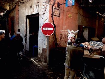 Man with horse on footpath by old building