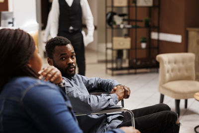 Side view of friends using mobile phone while sitting in cafe
