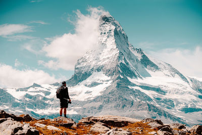 Rear view of man standing on snowcapped mountain