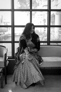 Rear view of woman sitting on seat at home