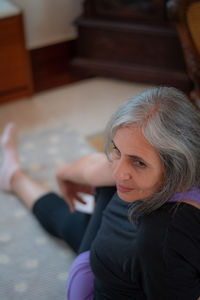 High angle view of senior woman sitting on rug at home