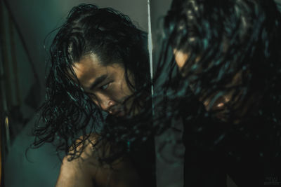 Close-up of man tossing long hair reflecting on mirror