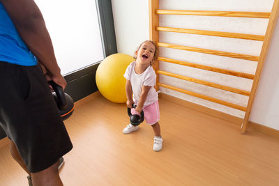 Little kid lifting kettlebell near father