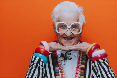 Portrait of smiling senior woman wearing eyeglasses against red background